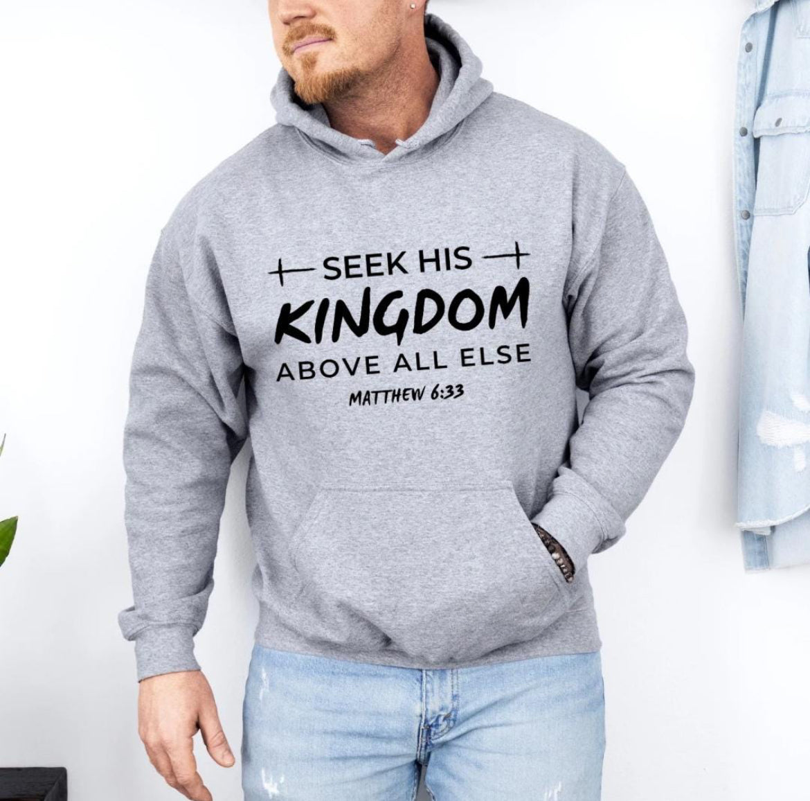 Gray hoodie that says, "Seek his Kingdom above all else." Underneath in smaller letters it says, "Matthew 6 33." There are two crosses as embellishments.