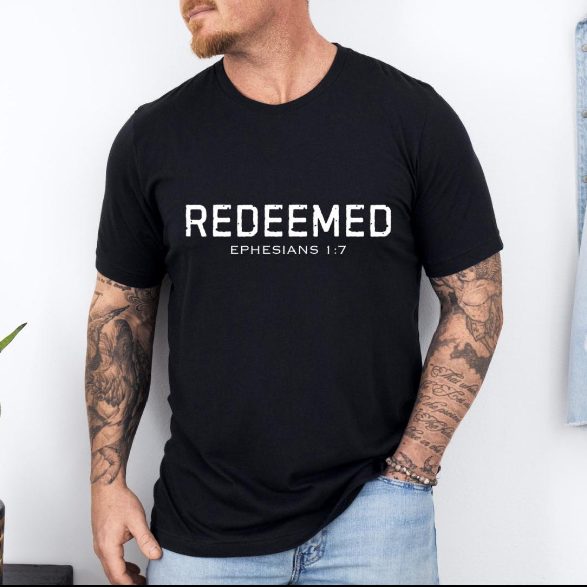 Black Crewneck t-shirt that says, “redeemed” in large distressed letters. Underneath in smaller letters it says, “Ephesians 1 7.”