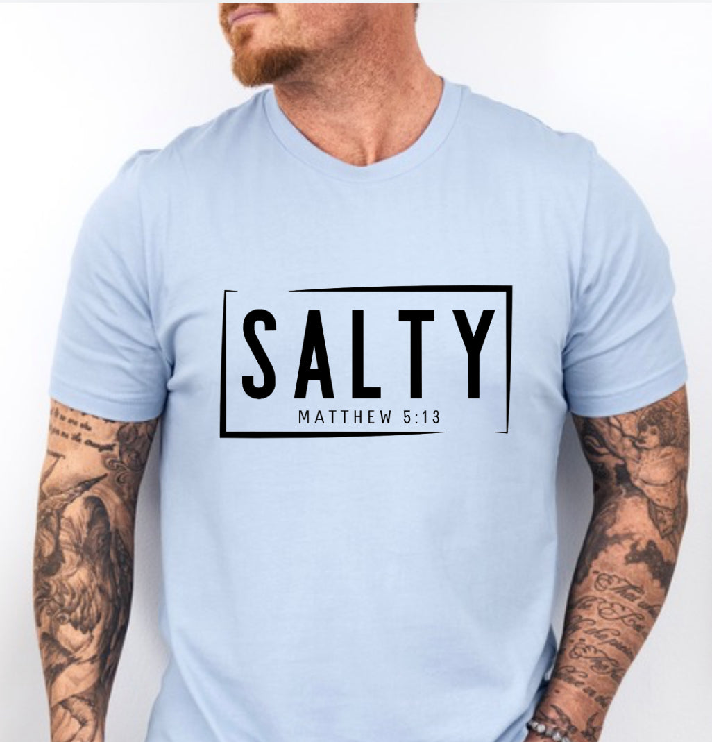 Baby blue crewneck t-shirt that says, “SALTY” in large capital letters. Underneath in smaller letters it says, “Matthew 5:13.” Christian Apparel