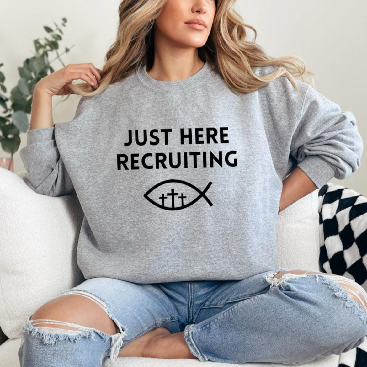 Light gray crewneck sweatshirt that says, "Just here recruiting" with the ichthus fish symbol with three crosses inside the fish.