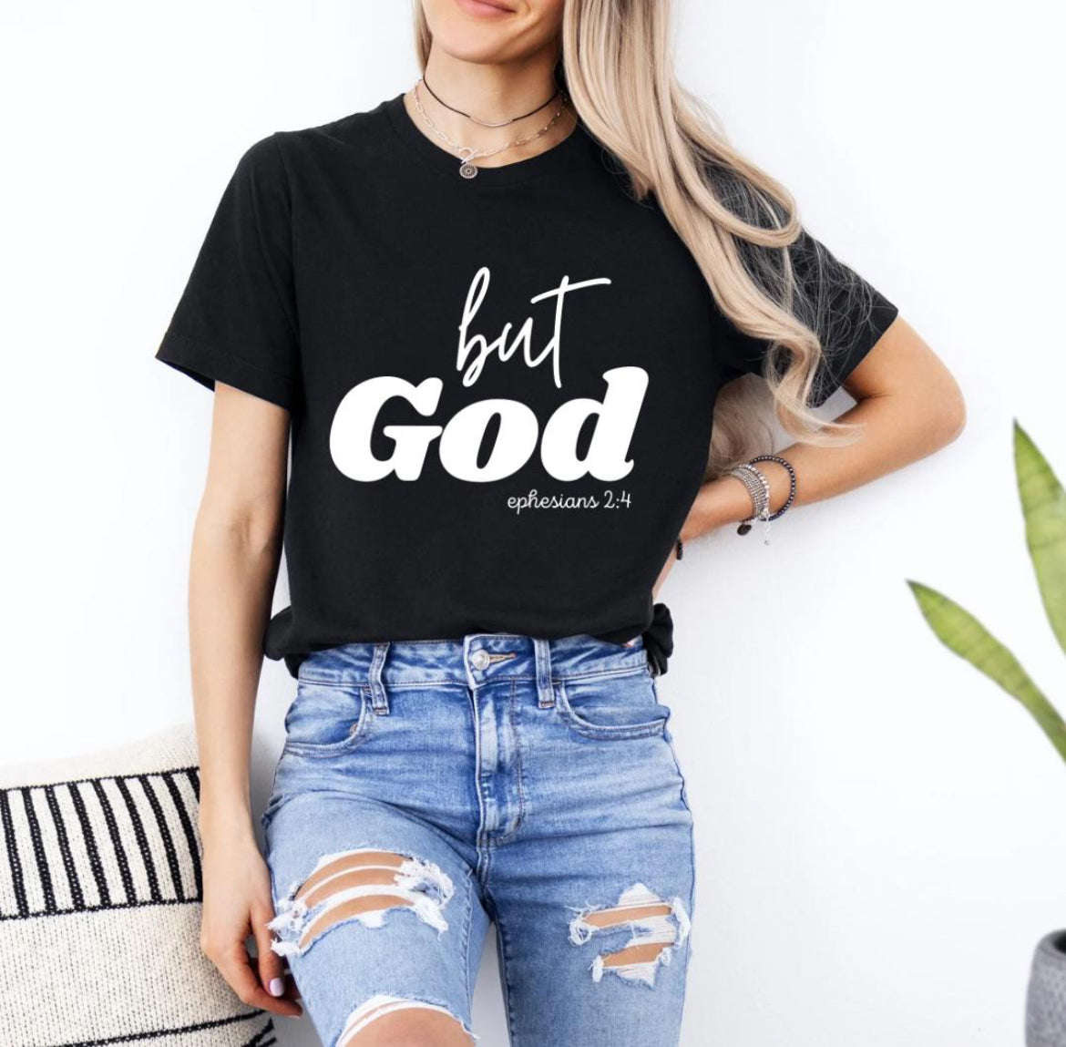 Black crewneck t-shirt that says, “but God” in large letters. Underneath in smaller letters it says, “Ephesians 2 4.”