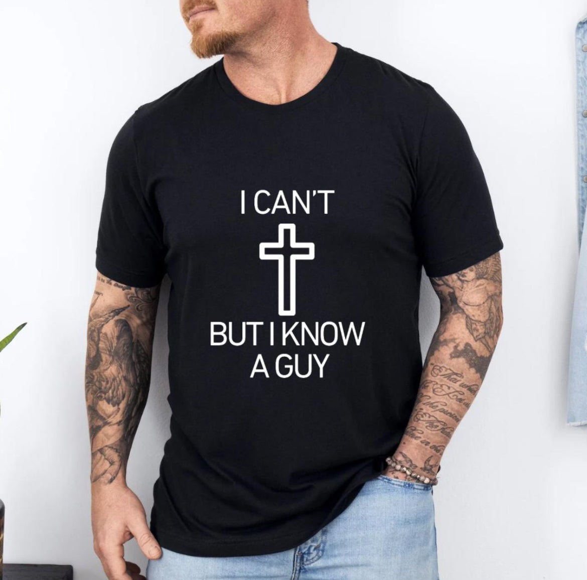 Black crewneck t-shirt that says, “I can’t but I know a guy” with a cross in the middle.