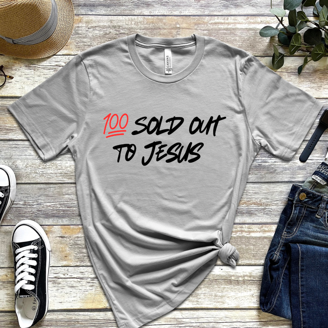 Grey crewneck t-shirt that says, “sold out to Jesus” with a “100 emoji”.