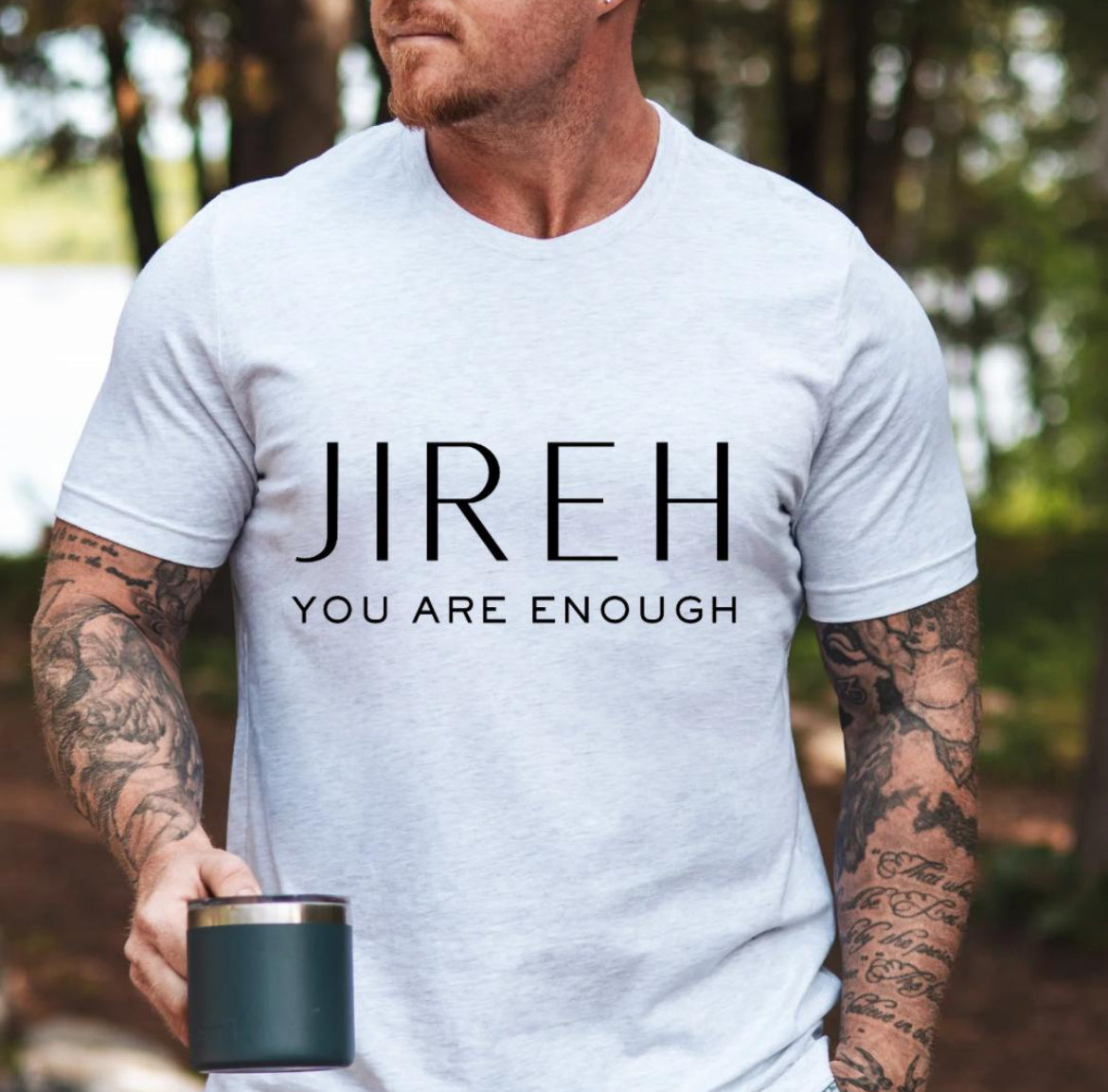 Ash white crewneck t-shirt that says, “jireh” in large letters. Underneath it says, “you are enough.”