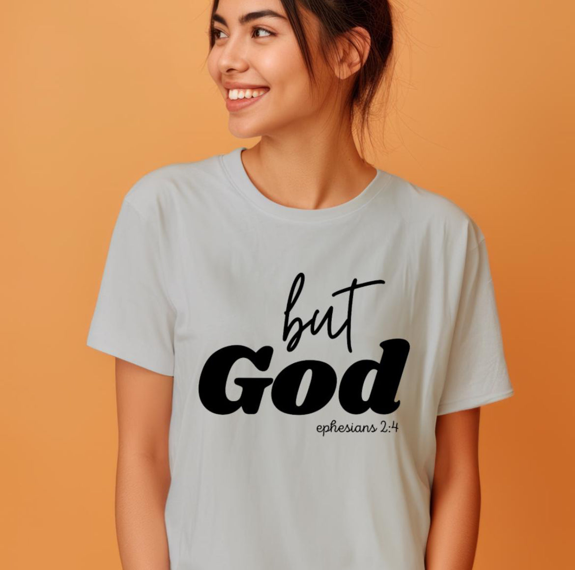 Gray crewneck t-shirt that says, “but God” in large letters. Underneath in smaller letters it says, “Ephesians 2 4.”