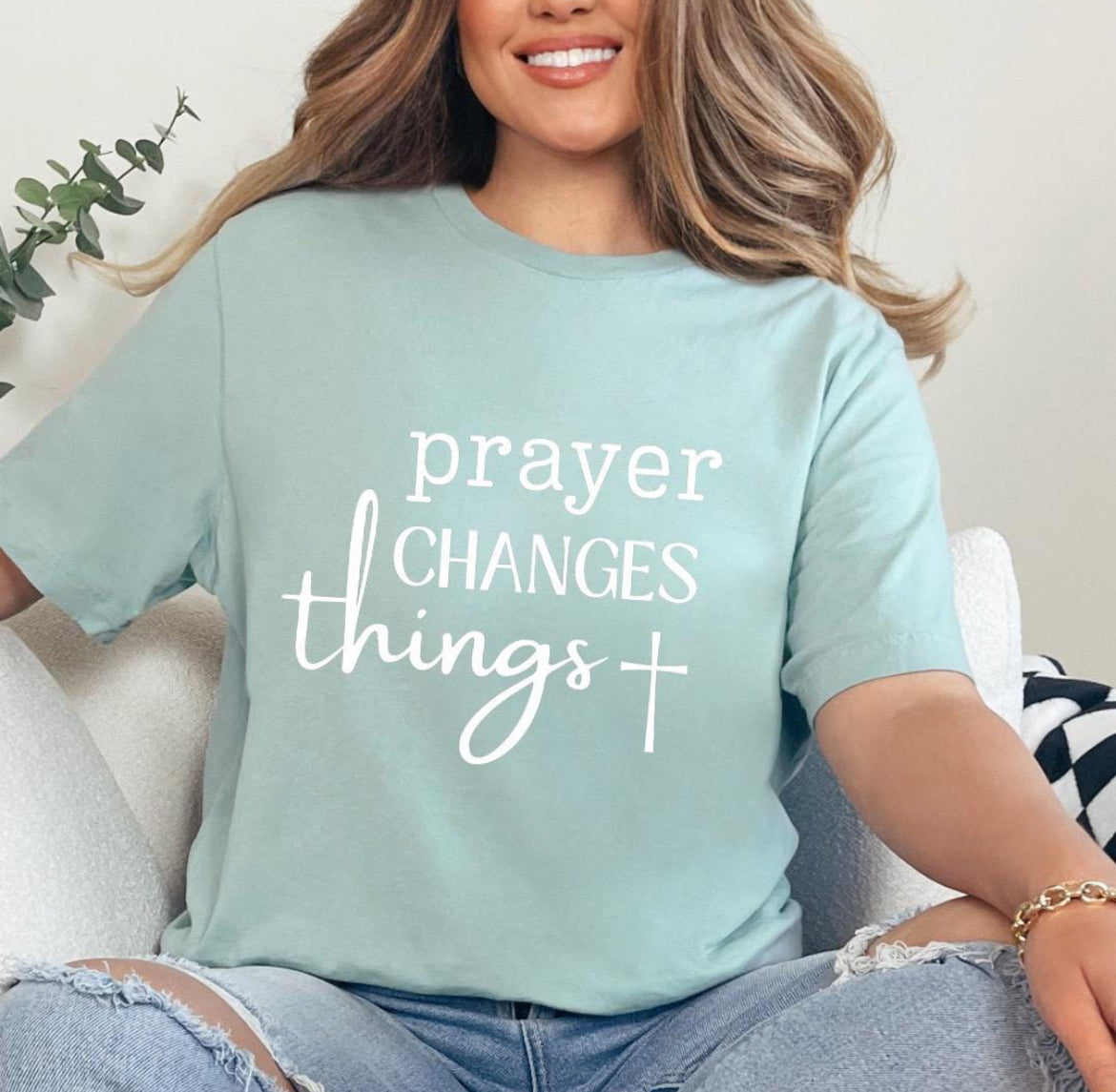 Dusty green crewneck t-shirt that says, “prayer changes things.”