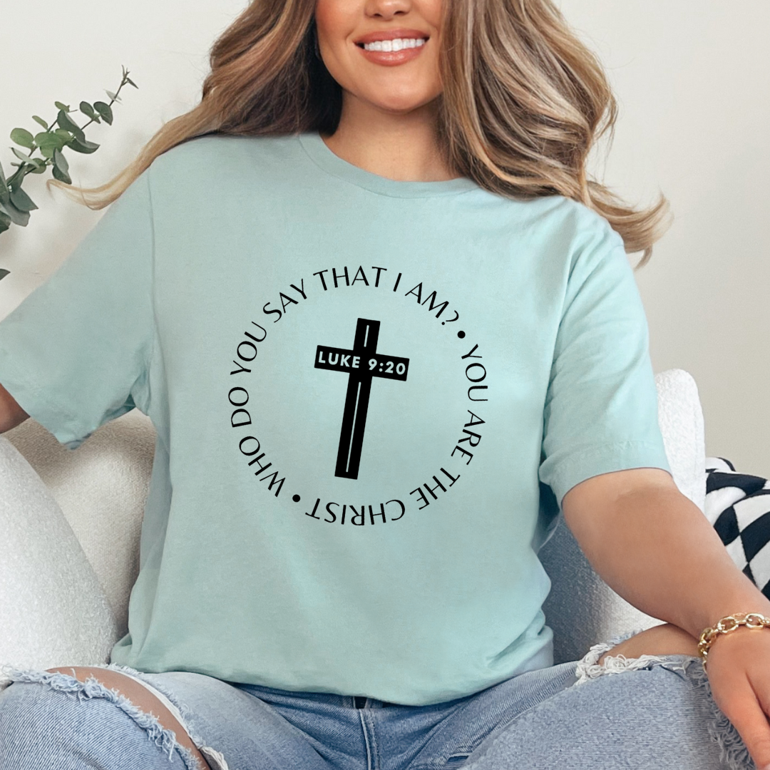 Dusty green crewneck t-shirt that says, “who do you say that I am? you are the Christ?” With a cross that says, “Luke 9:29” through the middle. 