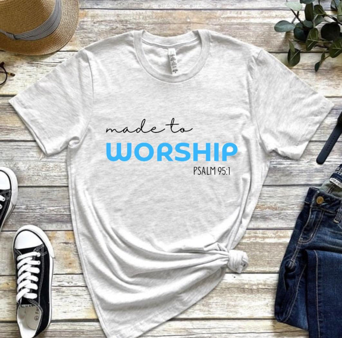 Ash white crewneck t-shirt that says, “made to worship” where the word “worship” is bold and blue. Underneath in smaller letters it says, “psalm 95 1.”