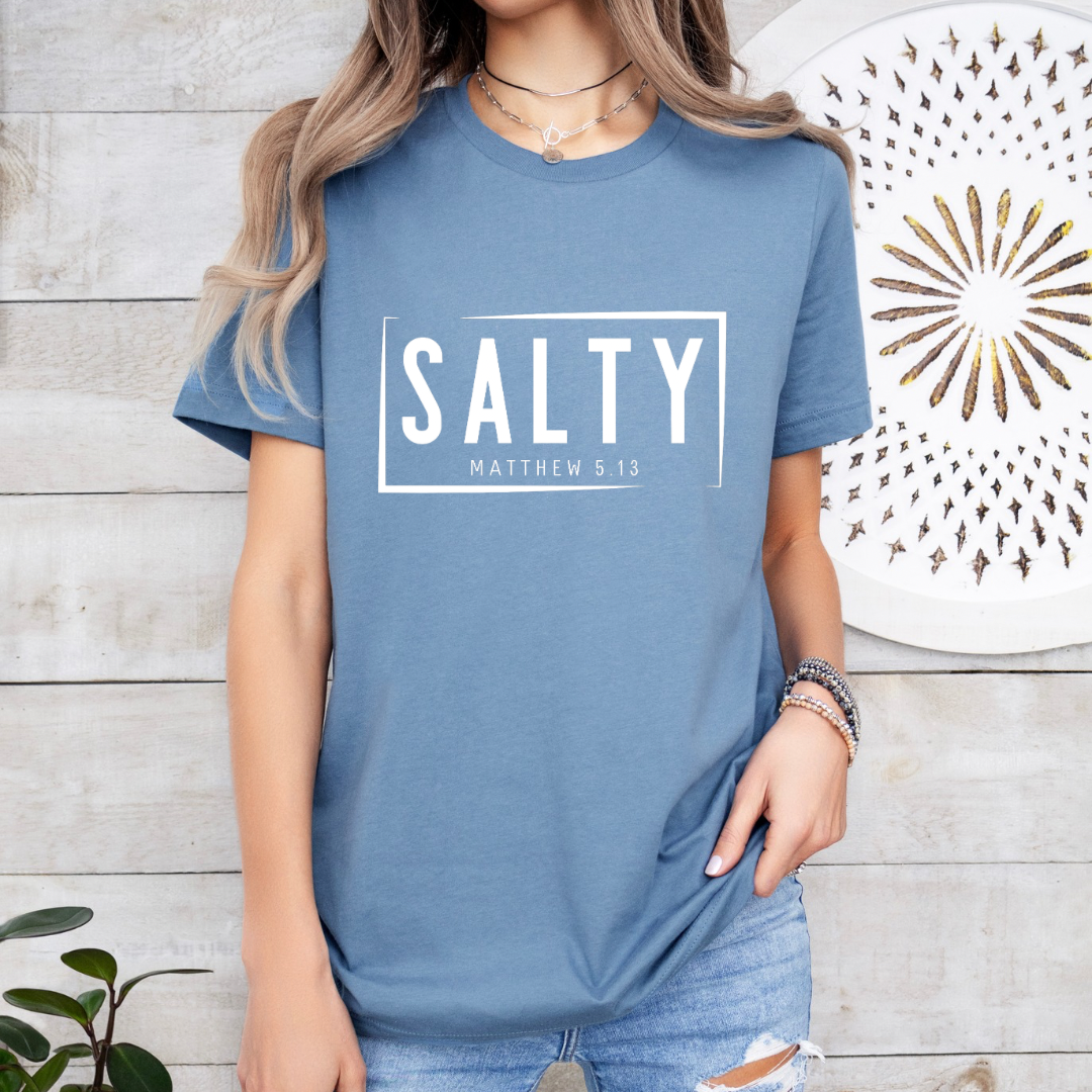 Steel blue crewneck t-shirt that says, “SALTY” in large capital letters. Underneath in smaller letters it says, “Matthew 5:13.” Christian Apparel