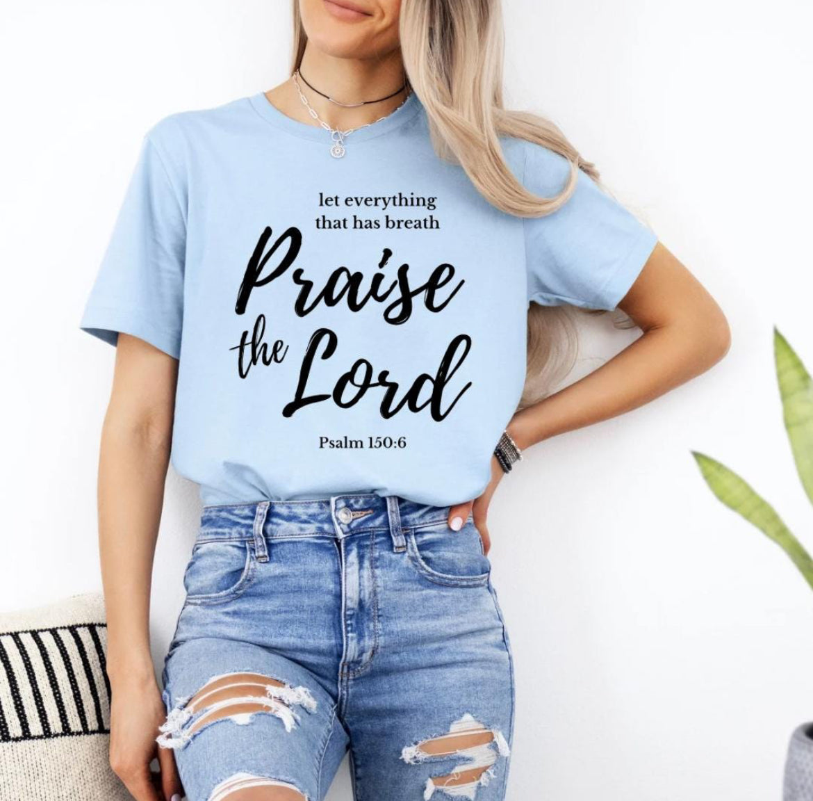 Baby blue crewneck t-shirt that says, “let everything that has breath praise the Lord” underneath in small letters it says, “Psalm 150 6.”