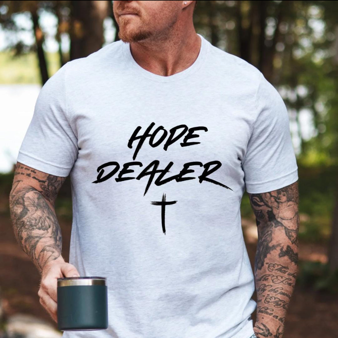 Ash white crewneck t-shirt that says, “Hope dealer” in an urban graffiti style writing with a cross. 