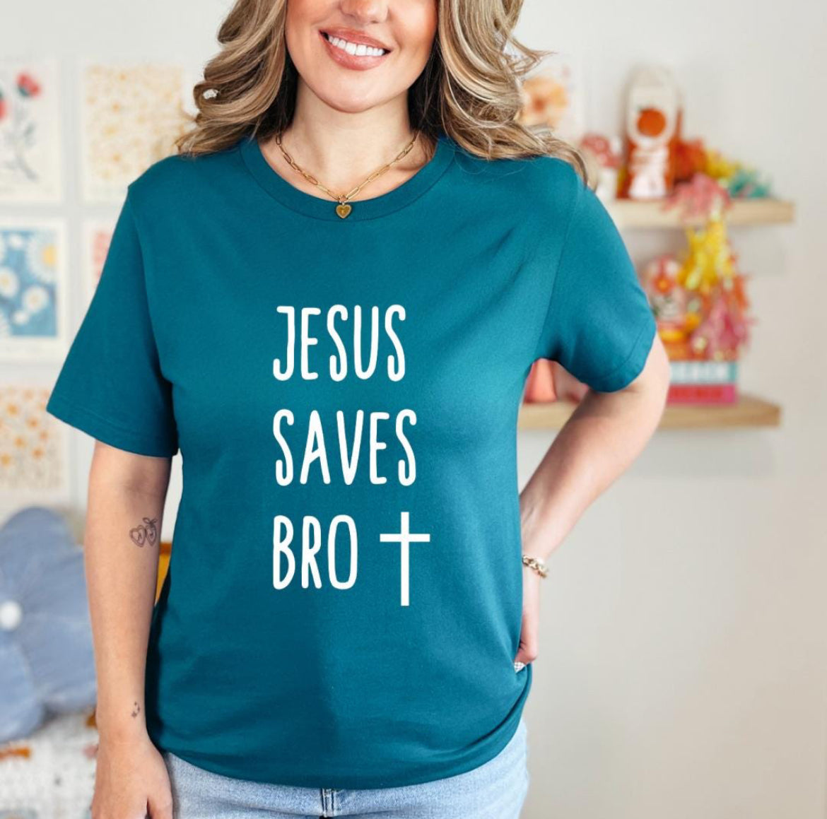 Deep teal crewneck t-shirt that says, “Jesus saves bro” with a cross. 