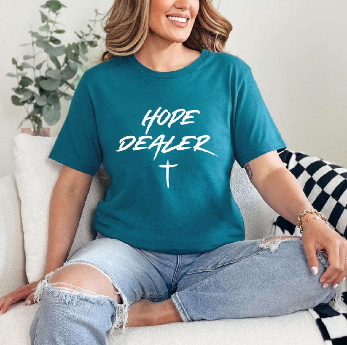 Deep teal crewneck t-shirt that says, “Hope dealer” in an urban graffiti style writing with a cross. 