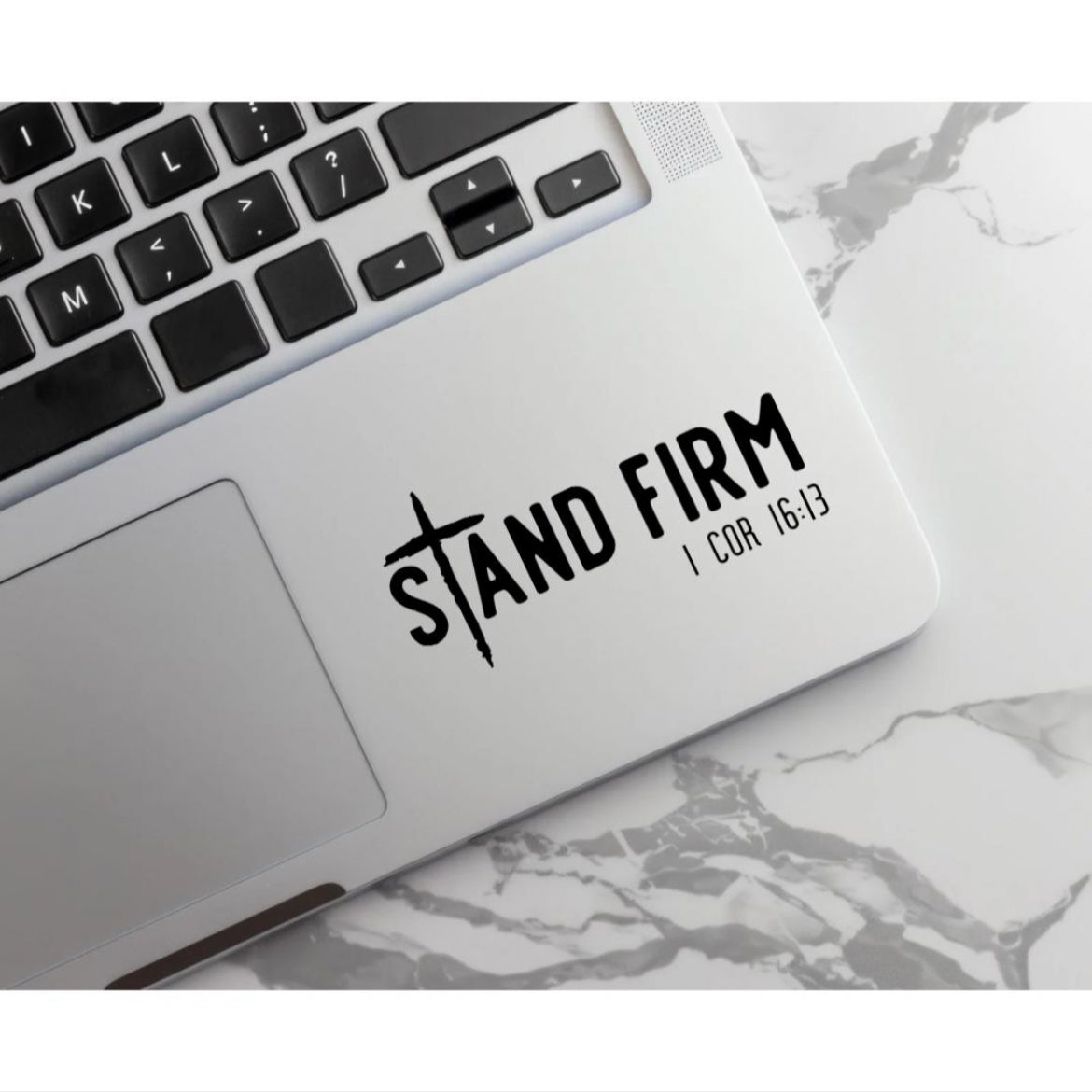 Laptop keyboard decal sticker  that says, “Stand firm” in large letters. The “T” in “stand” is a cross. Underneath in smaller letters it says, “1 Corinthians 16 13.”