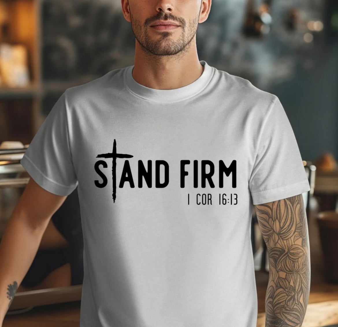 Grey Crewneck t-shirt that says, “Stand Firm” in large letters. The “t” in stand is a cross. Underneath in smaller letters it says, “1 Corinthians 16:13”.