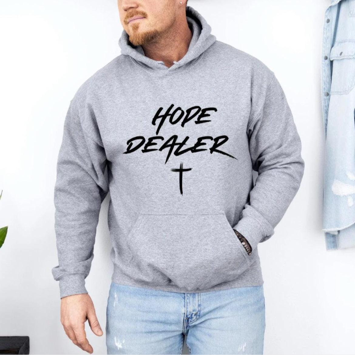 Grey hoodie sweatshirt that says, “Hope dealer” in graffiti style writing with a cross. 