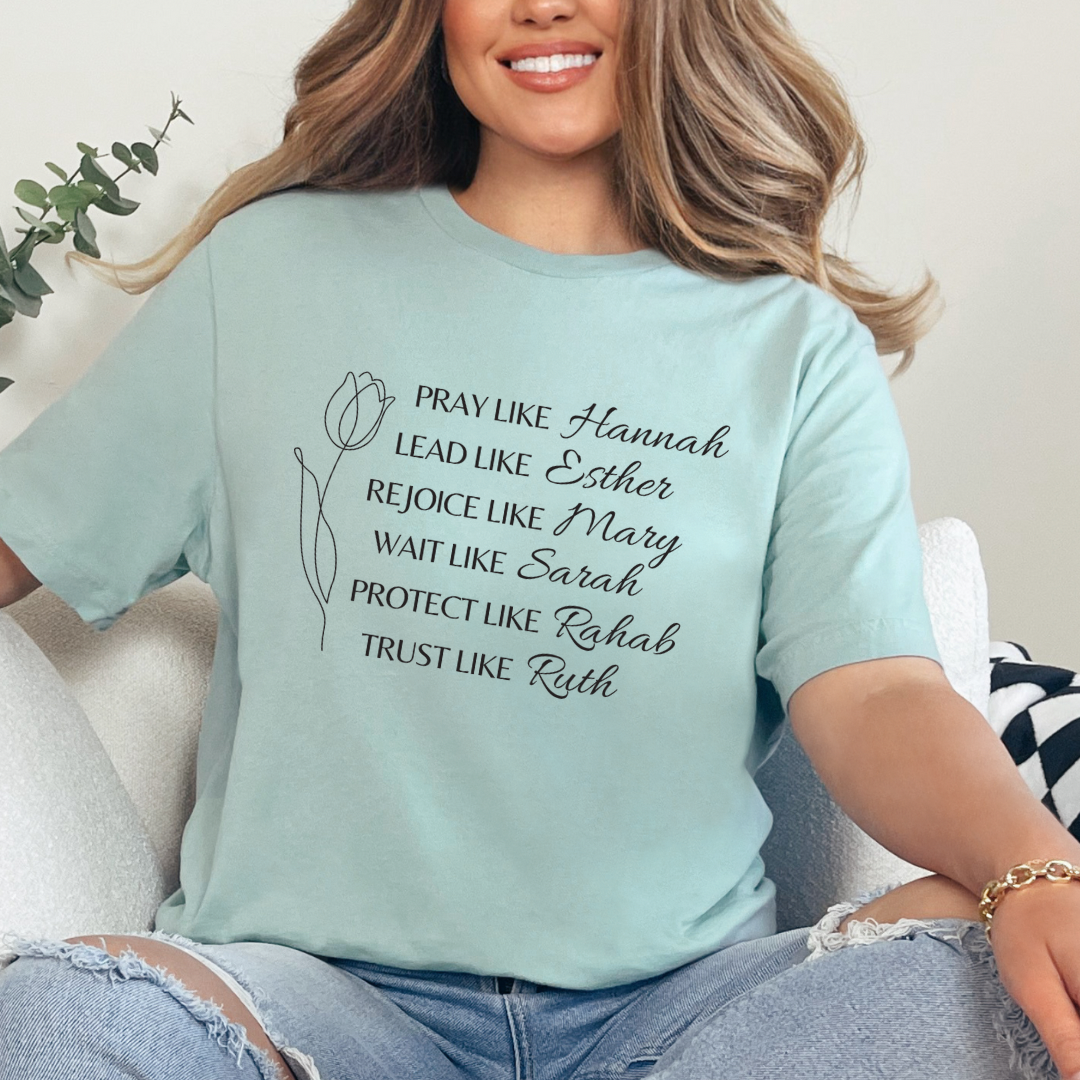 Dusty green crewneck t-shirt that says, "Pray like Hannah, lead like Esther, rejoice like Mary, wait like Sarah, protect like Rahab, trust like Ruth."