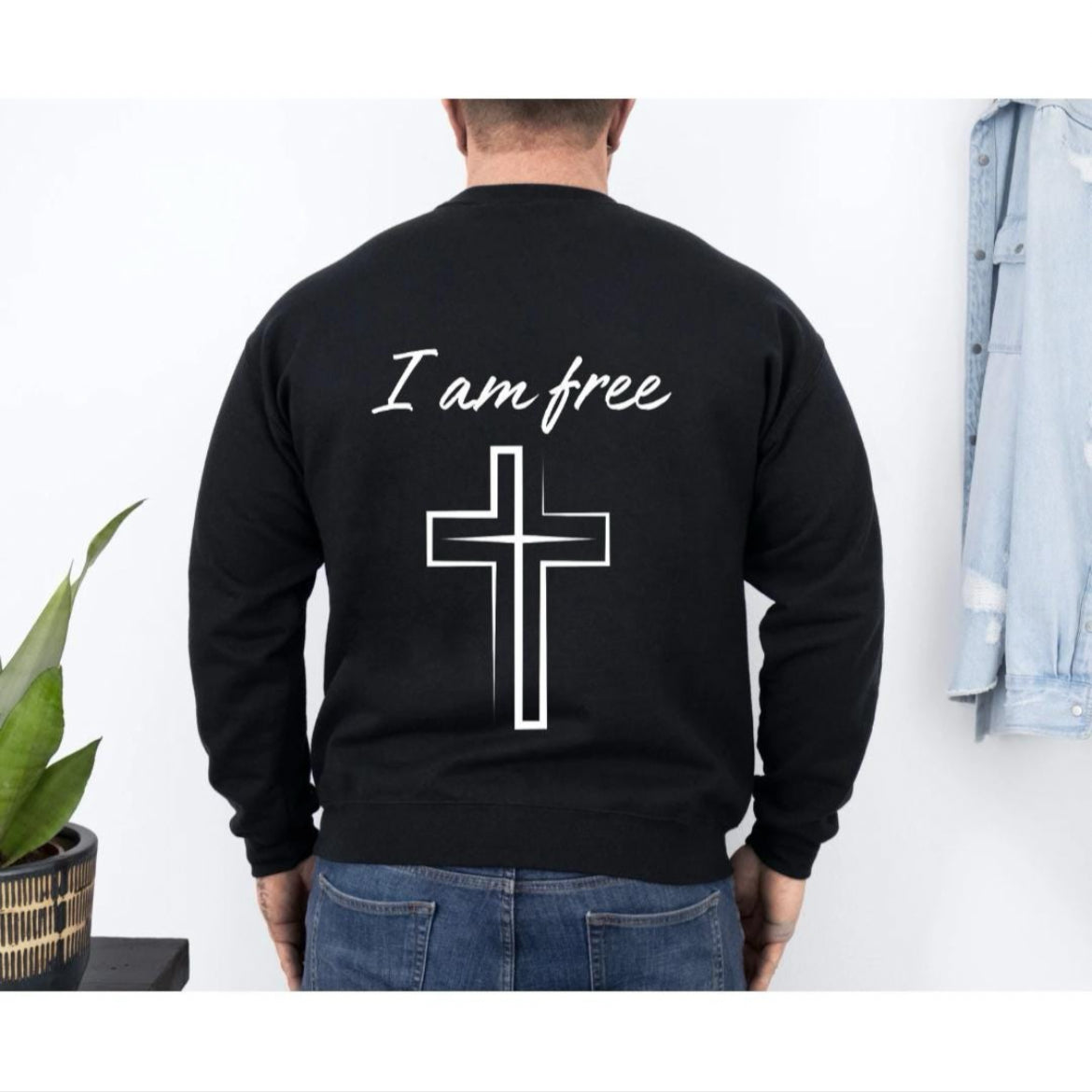 back of black crewneck sweatshirt that says, "I am free" with a large cross. 