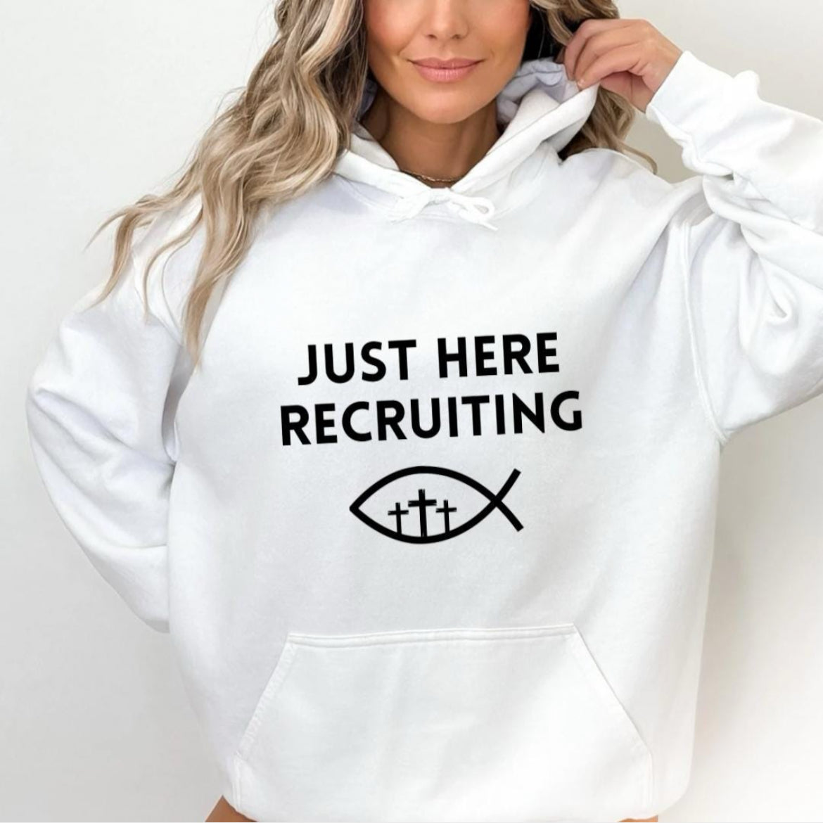 White hoodie sweatshirt that says, "Just here recruiting" with the ichthus fish symbol with three crosses inside the fish.