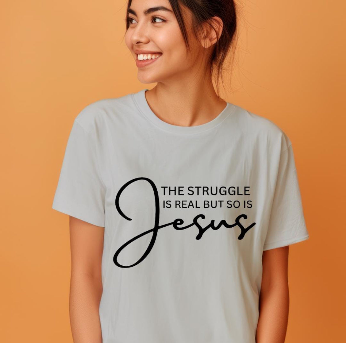 Gray crewneck t-shirt that says, “the struggle is real but so is Jesus”.