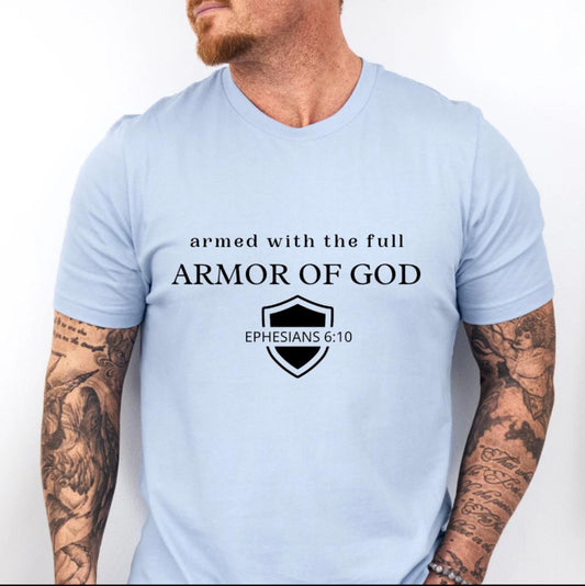 Baby blue crewneck t-shirt that says, “armed with the full armor of God.” There is a shield with “Ephesians 6 10” running through the middle. 