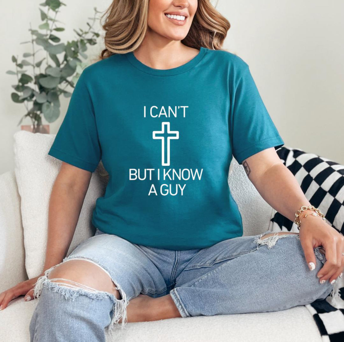 Deep teal crewneck t-shirt that says, “I can’t but I know a guy” with a cross in the middle.