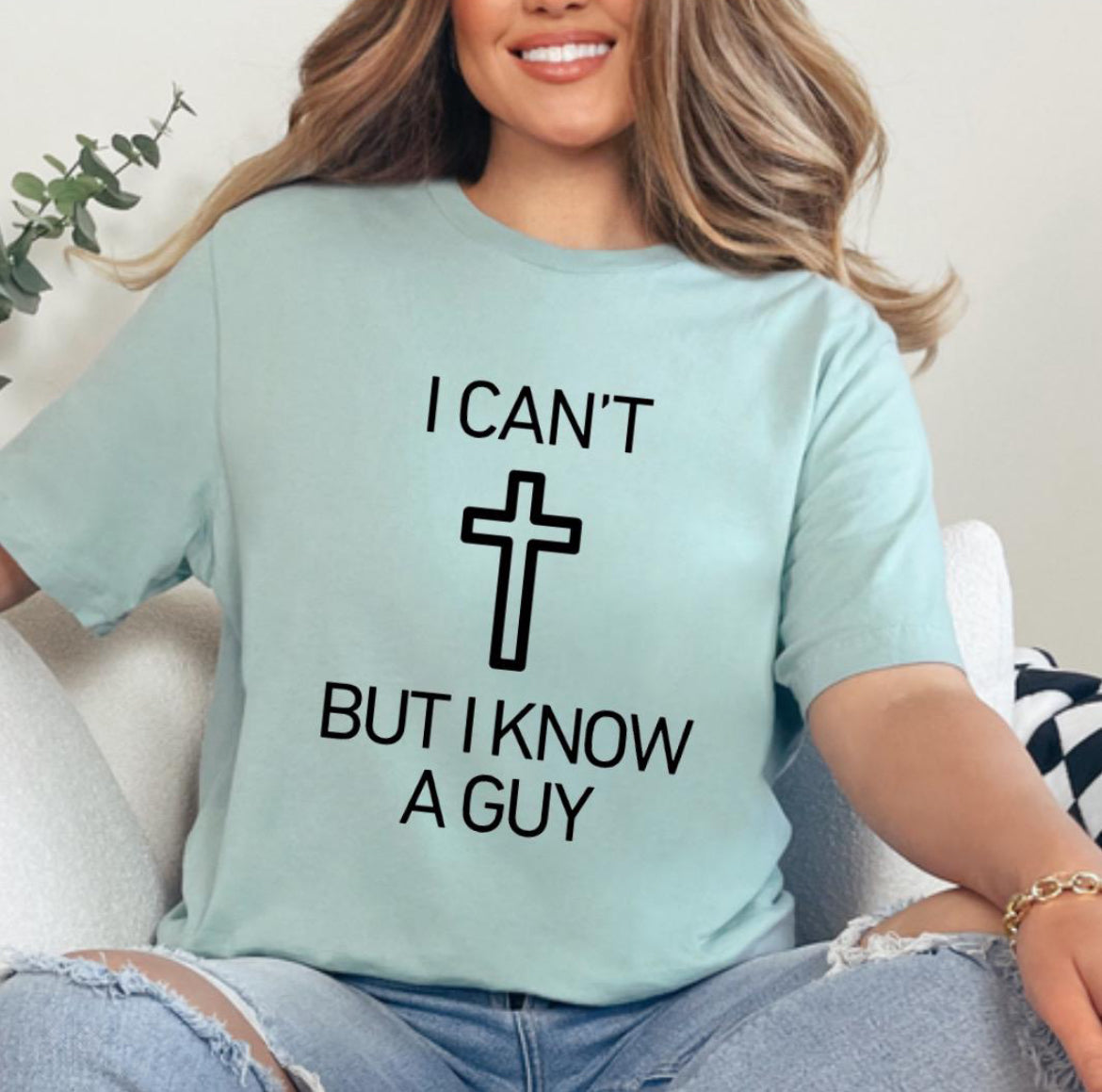 Dusty green crewneck t-shirt that says, “I can’t but I know a guy” with a cross in the middle.