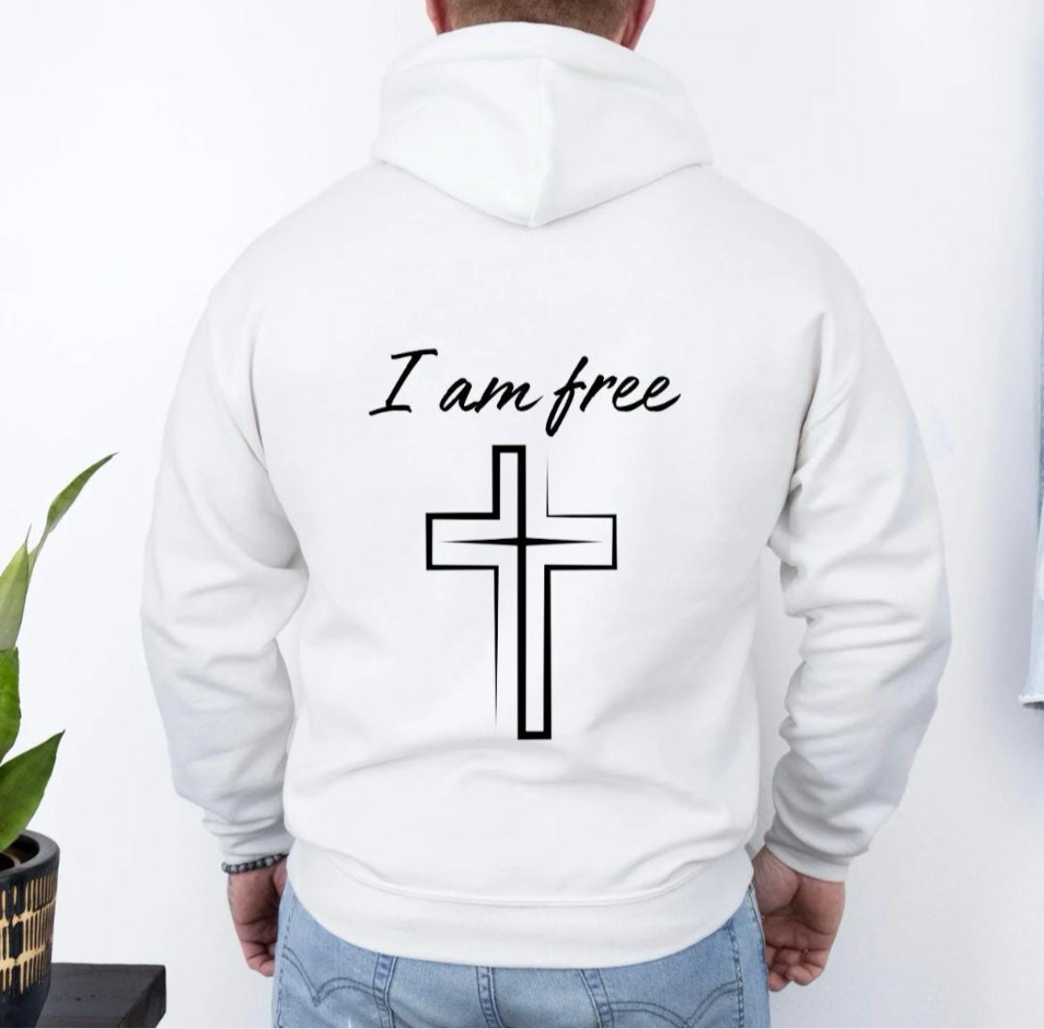 Back of a white hoodie that says, "I am free" with a large cross. 