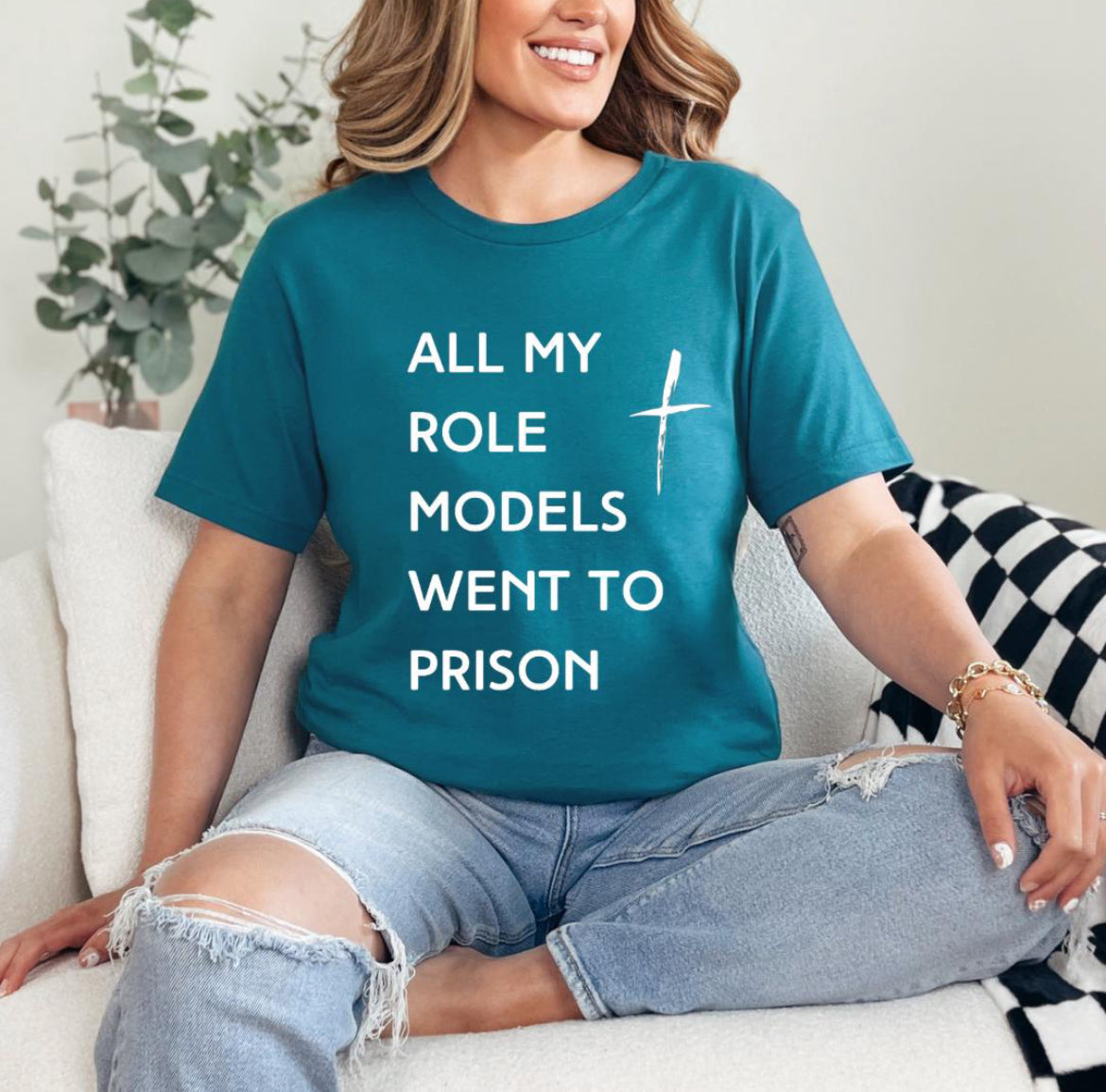 Deep teal crewneck t-shirt that says, “all my role models went to prison” with a cross. 