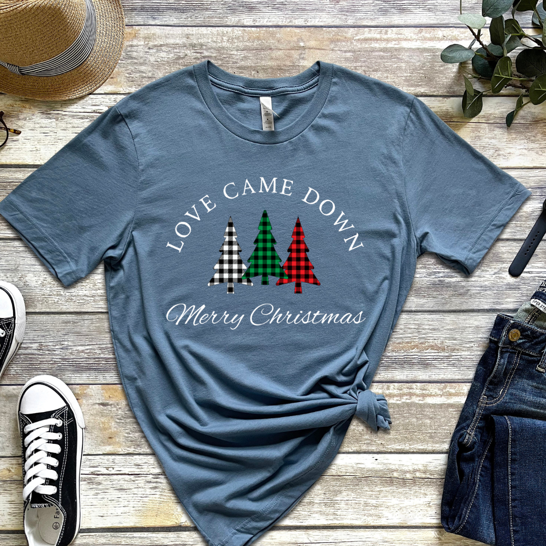 Steel blue crewneck t-shirt that says, "Love came down. Merry Christmas." It features 3 Christmas trees in buffalo plaid green, red and white.