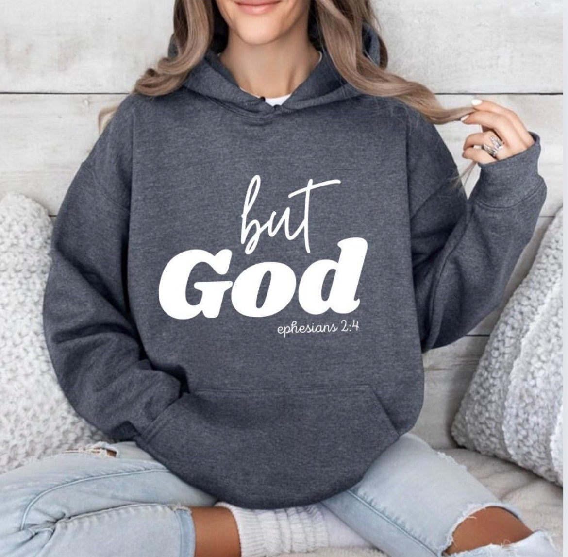 Dark gray heather hooded sweatshirt that says, "But God" in large letters. Underneath it says, "Ephesians 2 verse 4" in smaller letters. 