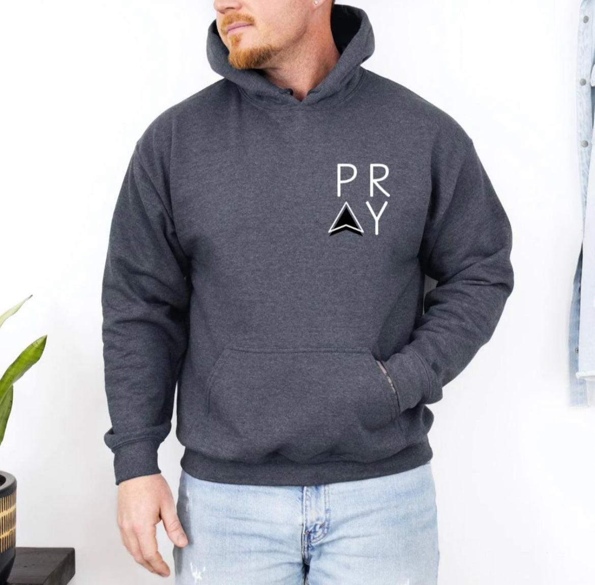 Dark hoodie that says, "PRAY" where the A is an arrow in the front left-hand corner of the hoodie.