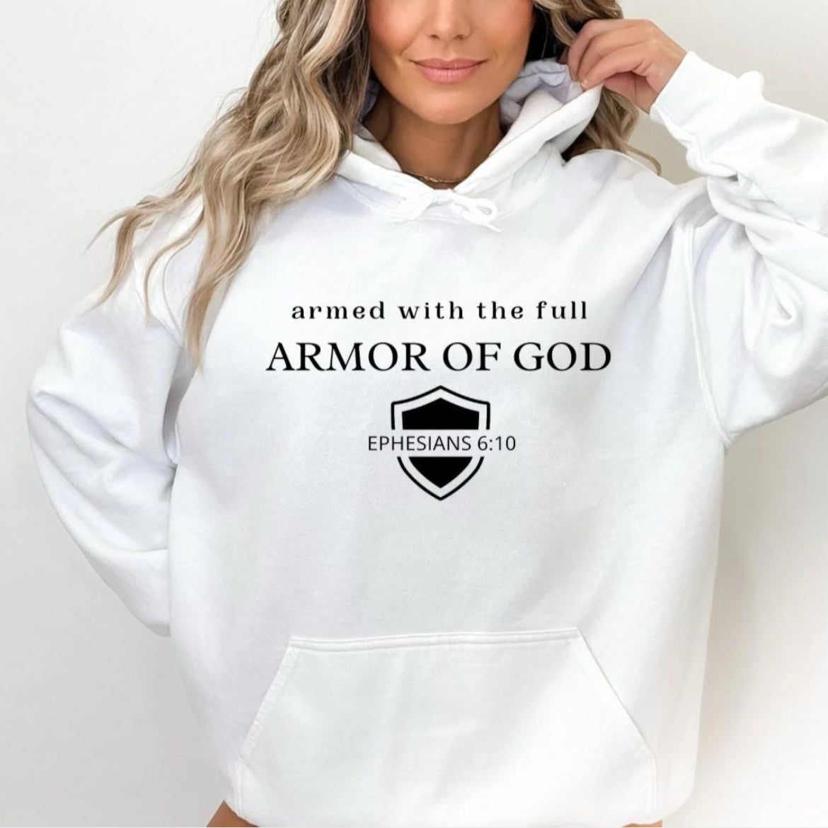 White hoodie that says, "armed with the full armor of God." Underneath is a shield and in the middle of the shield it says, "Ephesians 6 10."