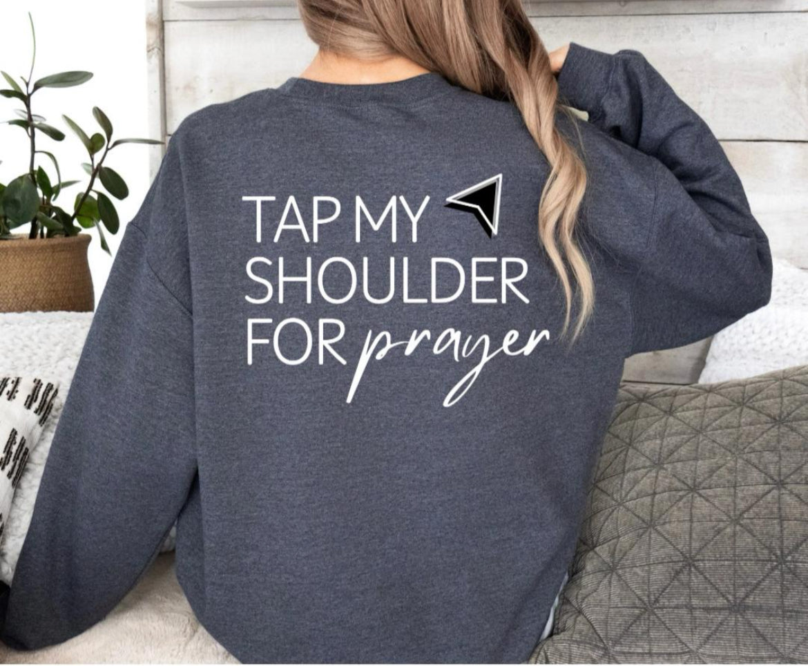 Back of dark grey crewneck sweatshirt that has an aesthetic arrow pointing towards the shoulder that says, "Tap my shoulder for prayer."