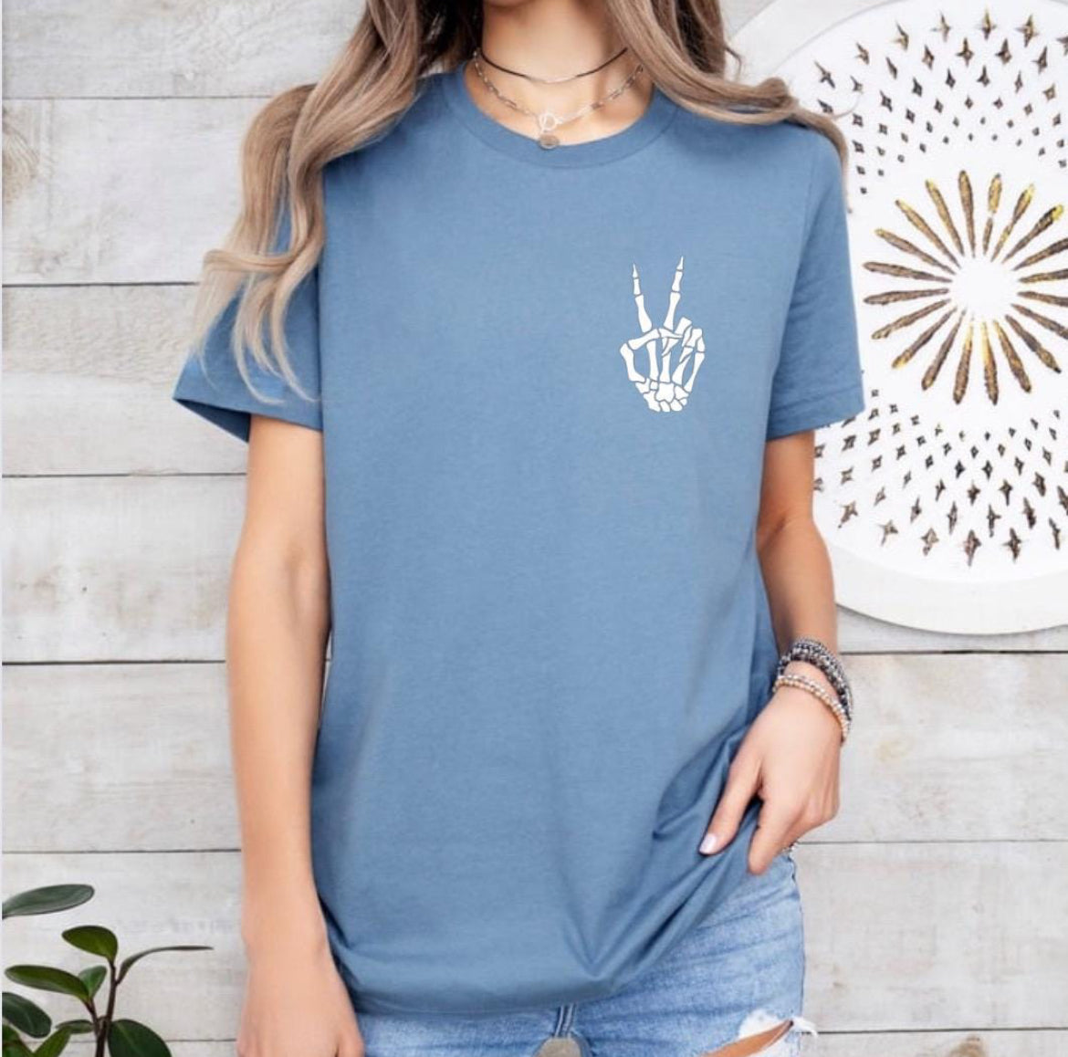 Steel blue crewneck t-shirt that has a small bones hand peace sign in the upper left-hand corner. 