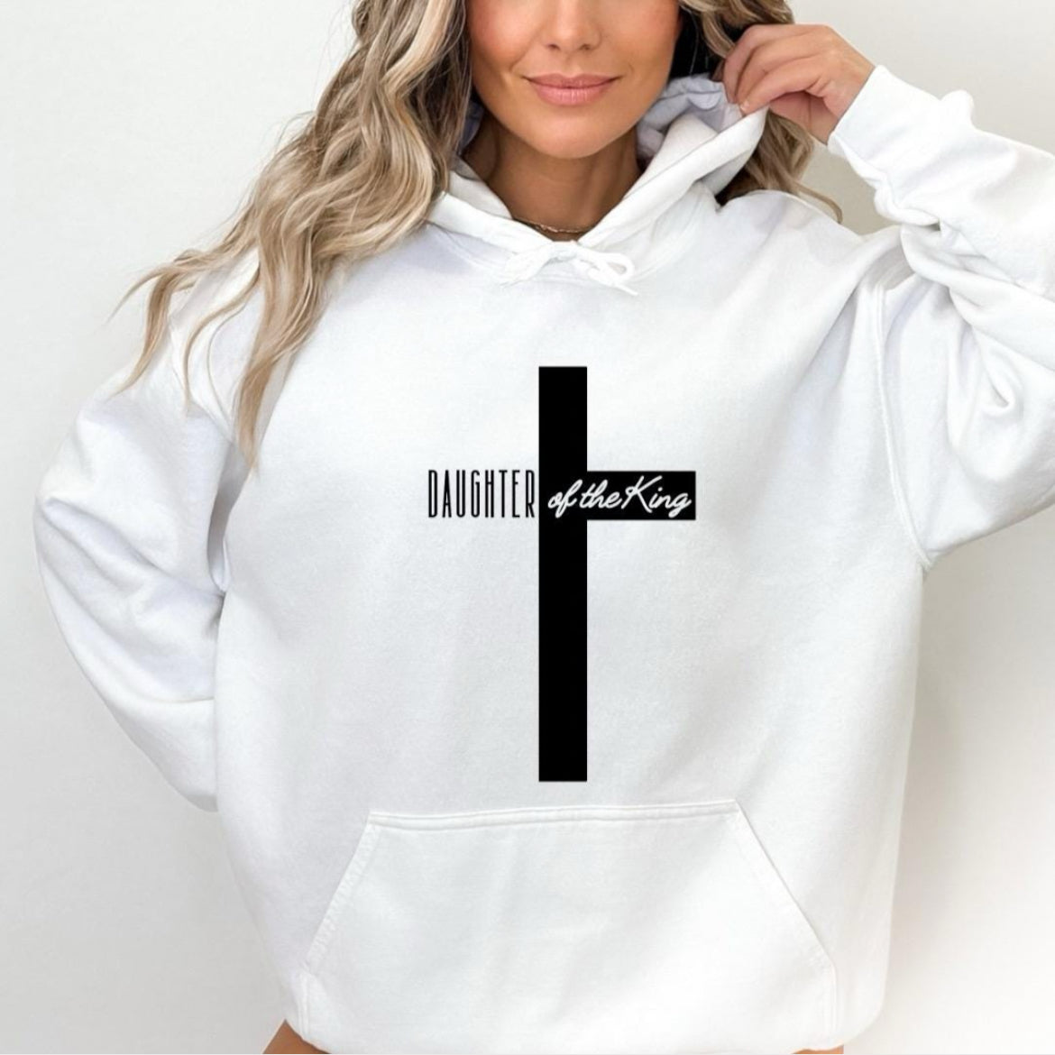 White hooded sweatshirt with a large cross that says, "Daughter of the King," On the sleeve it says, "1 John 3:1."