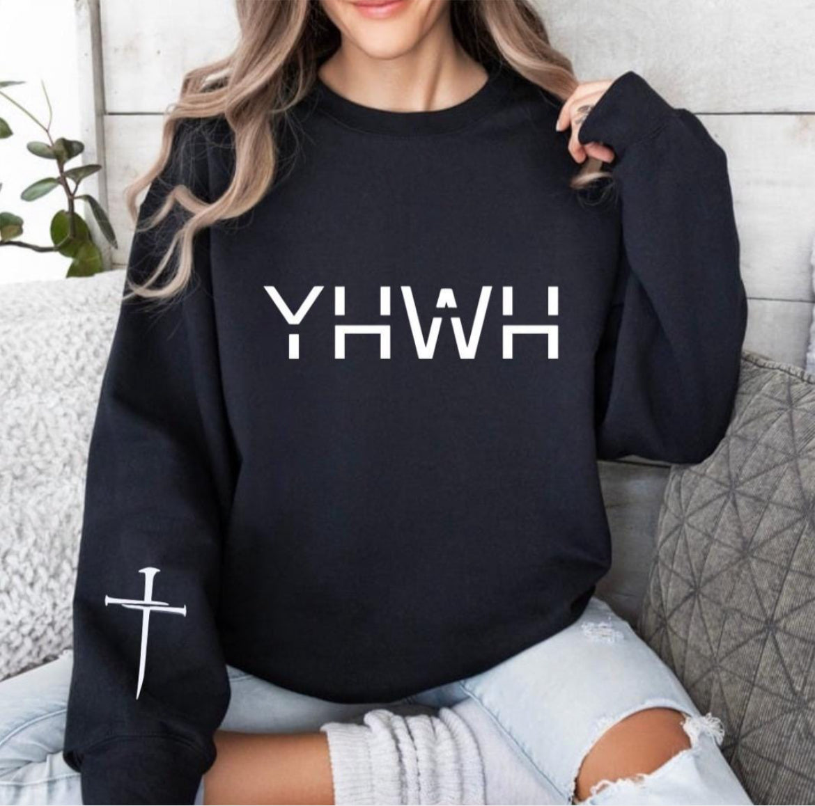 Black crewneck sweatshirt that says, "YHWH" with a cross on the sleeve. 