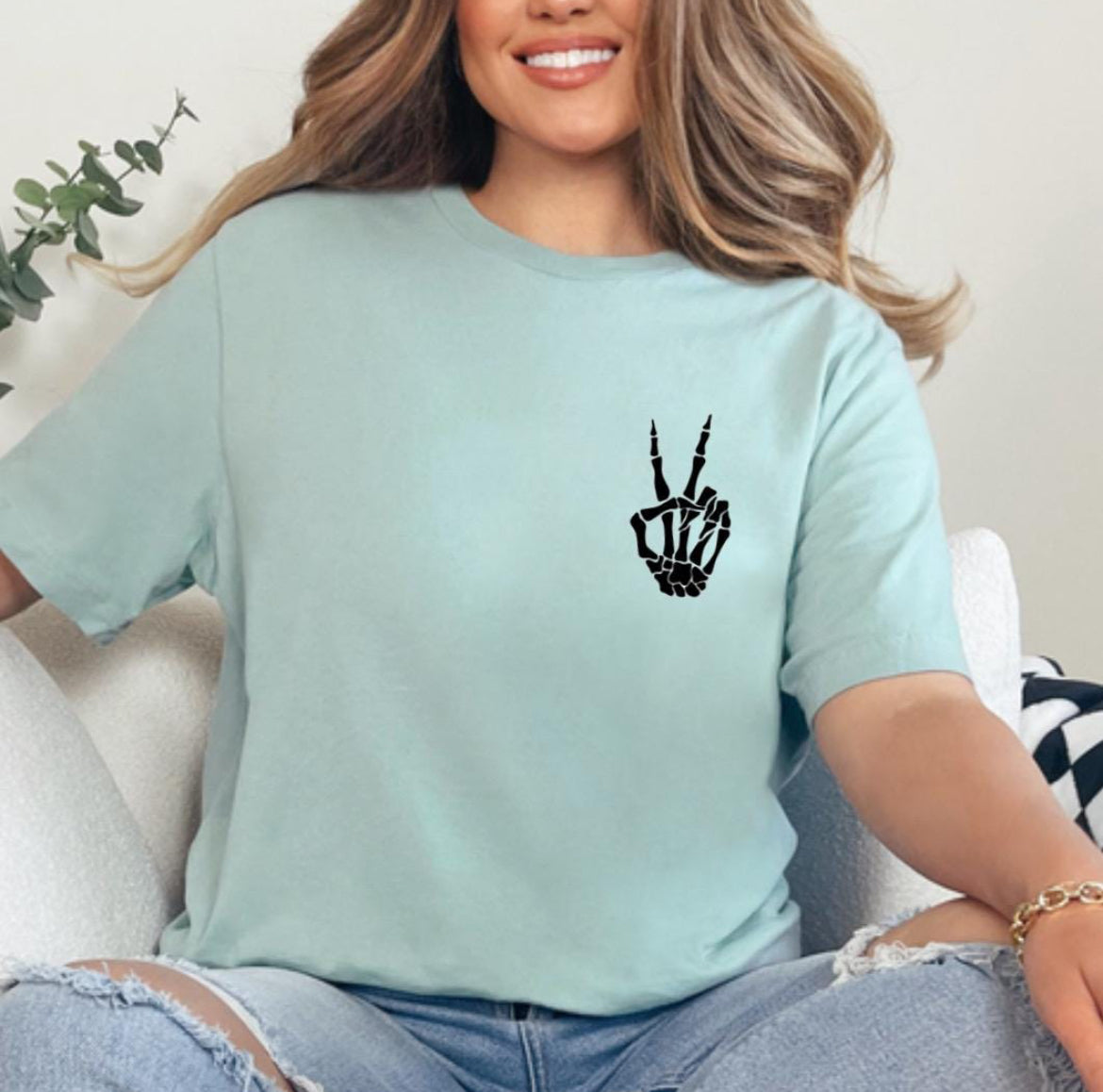 Dusty green crewneck t-shirt that has a small bones hand peace sign in the upper left-hand corner. 