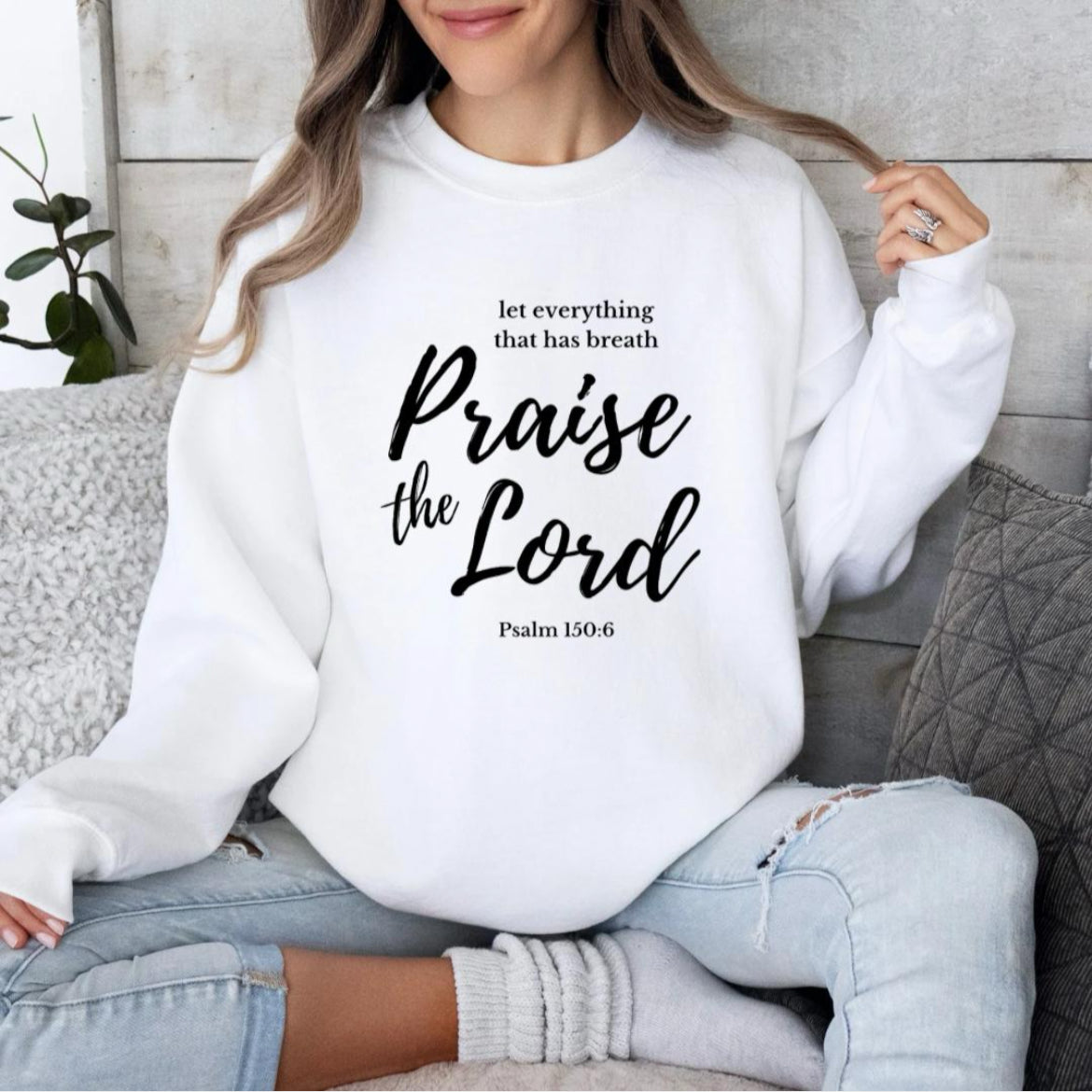 White crewneck sweatshirt that says, "Let everything that has breath Praise the Lord." Underneath it says, "Psalm 150 verse 6."