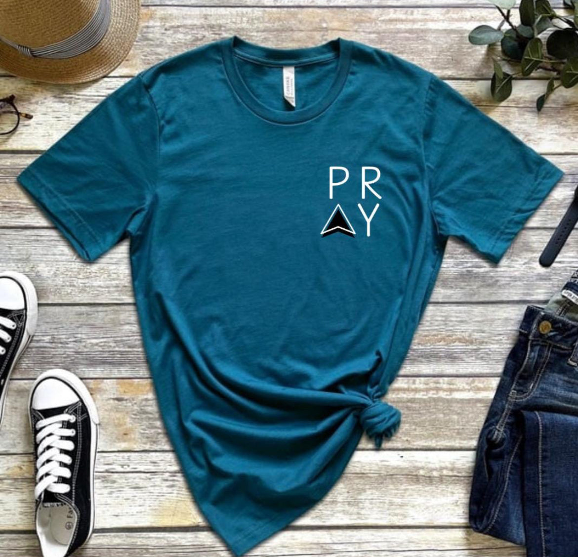 Deep teal Crewneck t-shirt that says, “PRAY” up in the left-hand corner of the shirt. 