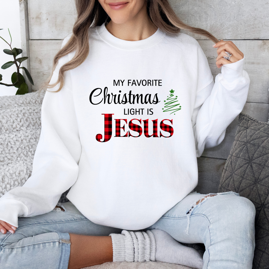 White crewneck sweatshirt that says, "My favorite Christmas light is Jesus." Jesus is in buffalo plaid red with a green Christmas tree graphic.