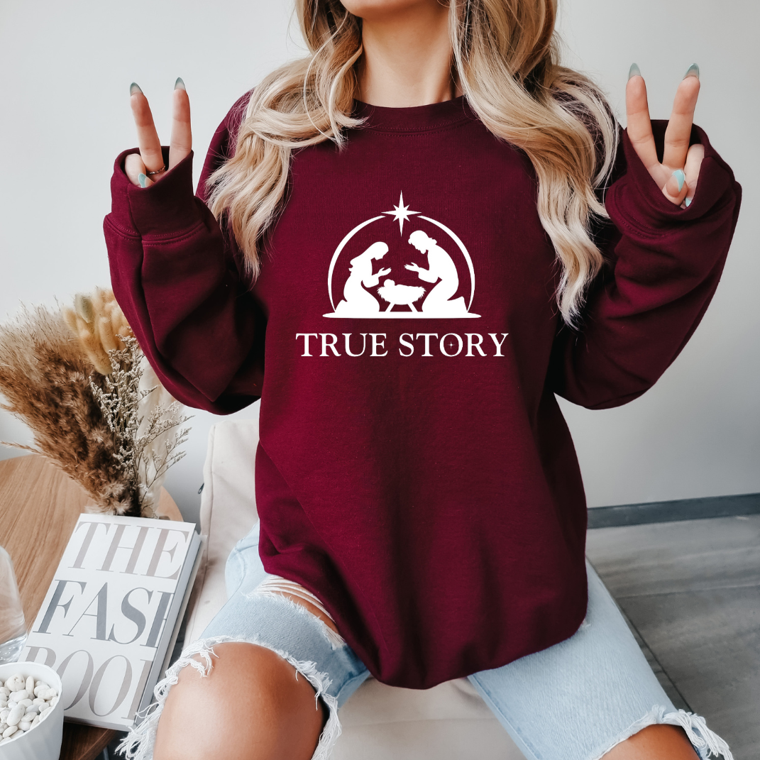 Maroon sweatshirt that says, "True story" with an image of Baby Jesus, Mary & Joseph in a manger.