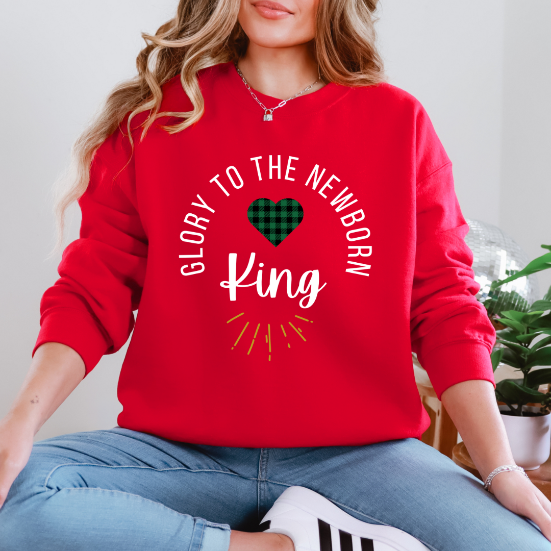 Red crewneck sweatshirt that says, "Glory to the newborn King" with gold embellishment and buffalo plaid red heart.