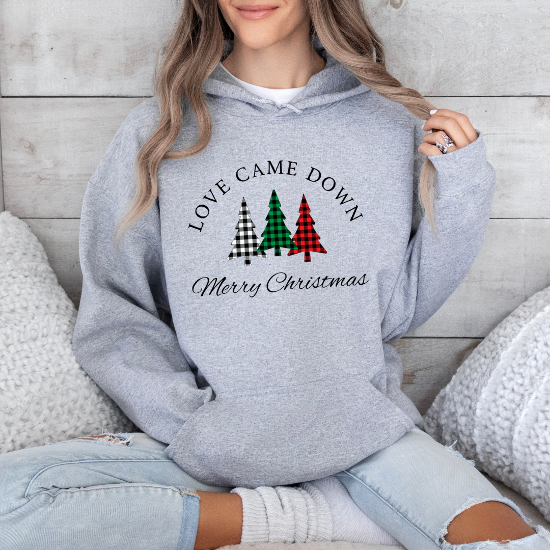 Grey hoodie sweatshirt that says, "Love came down. Merry Christmas" with three Christmas trees in buffalo plaid green, red and black. 