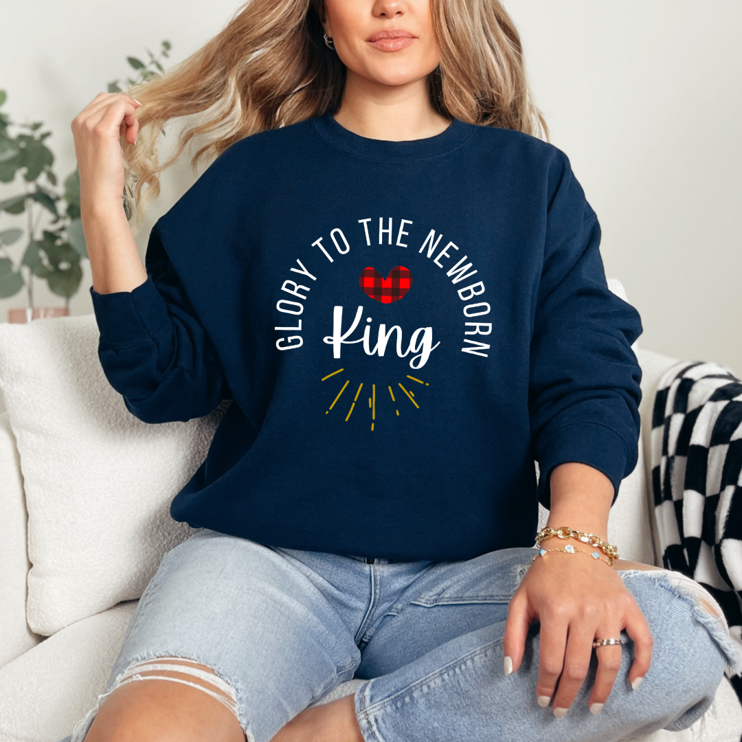 Navy crewneck sweatshirt that says, "Glory to the newborn King" with gold embellishment and buffalo plaid red heart.