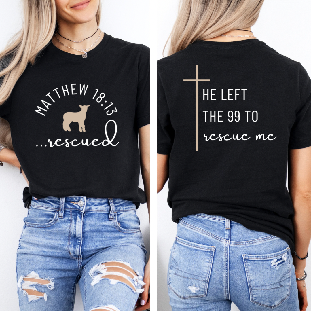 Black crewneck T-Shirt that says, "He left the 99 to rescue me" with a large tan cross. On the front it says, "Matthew 18:13 rescued" with a tan sheep. 