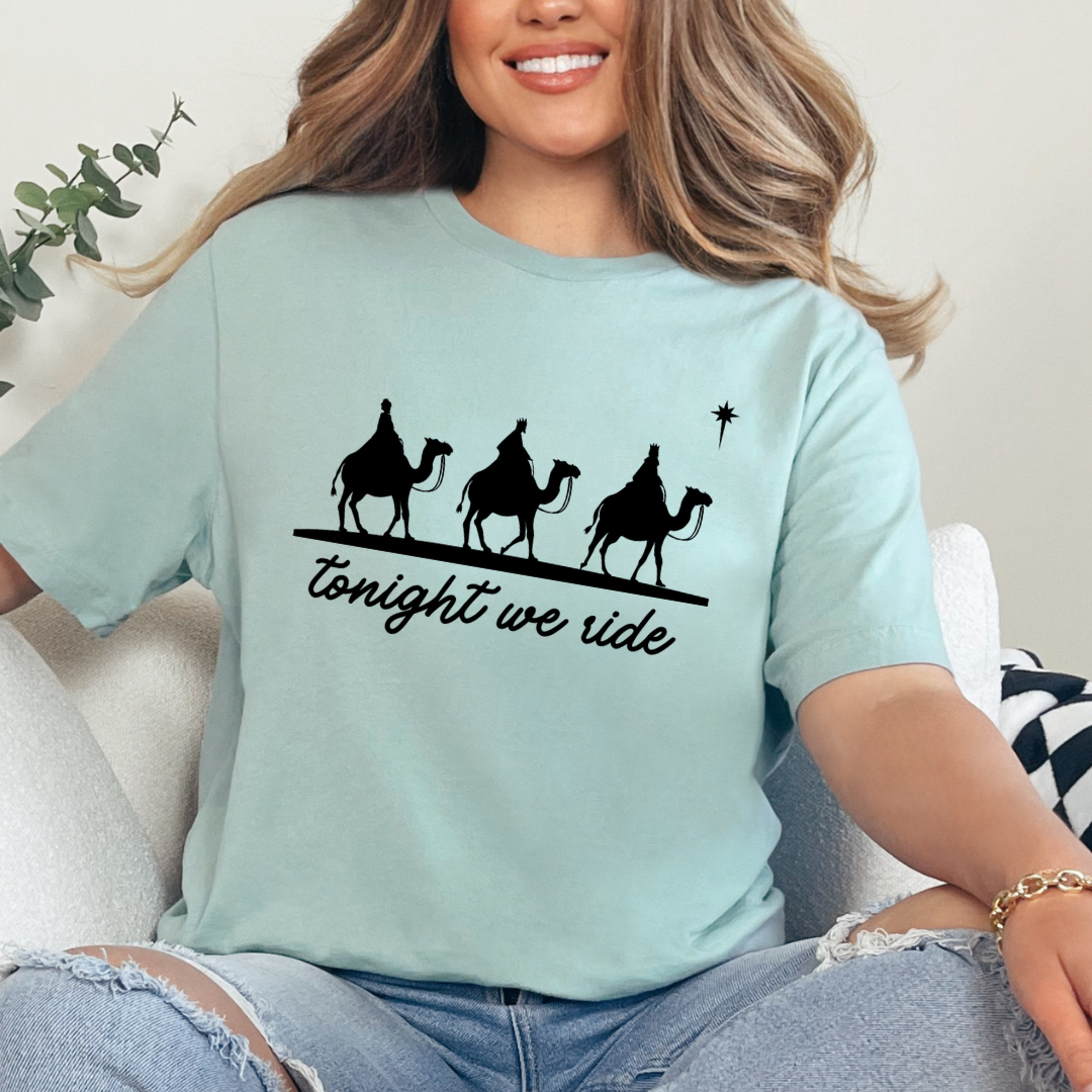 Dusty green crewneck t-shirt that says, “tonight we ride” with an image of the three wisemen riding on camels towards the Christmas star.