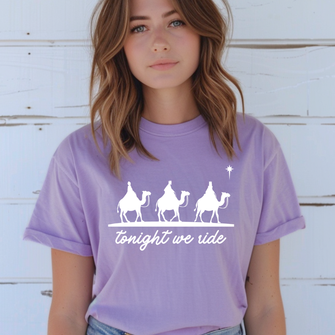 Lavender crewneck t-shirt that says, “tonight we ride” with an image of the three wisemen riding on camels towards the Christmas star.