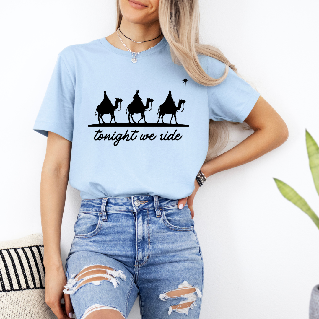 Baby blue crewneck t-shirt that says, “tonight we ride” with an image of the three wisemen riding on camels towards the Christmas star.