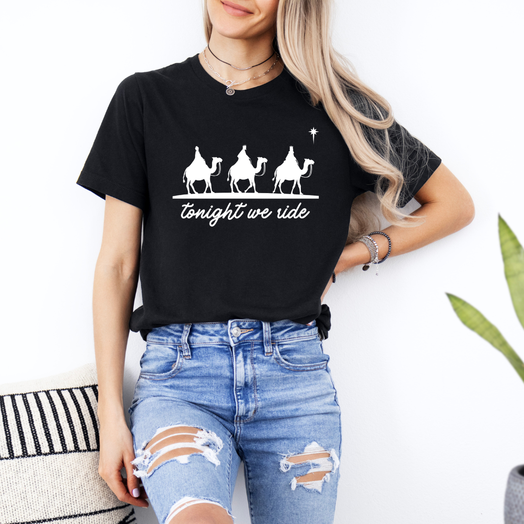 Black crewneck t-shirt that says, “tonight we ride” with an image of the three wisemen riding on camels towards the Christmas star.